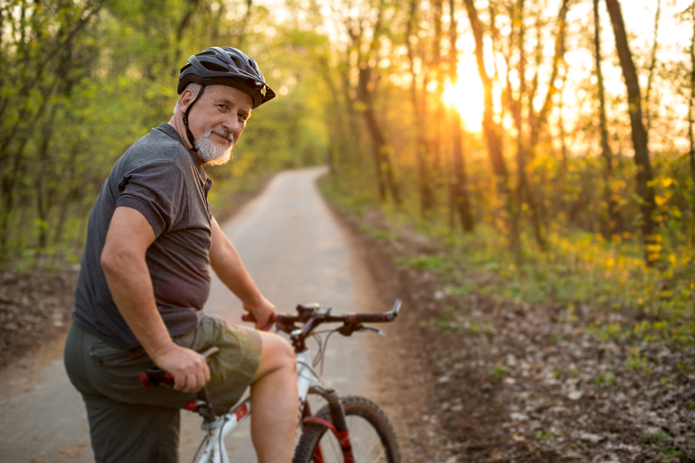 An elderly man having a casual bike ride in the woods