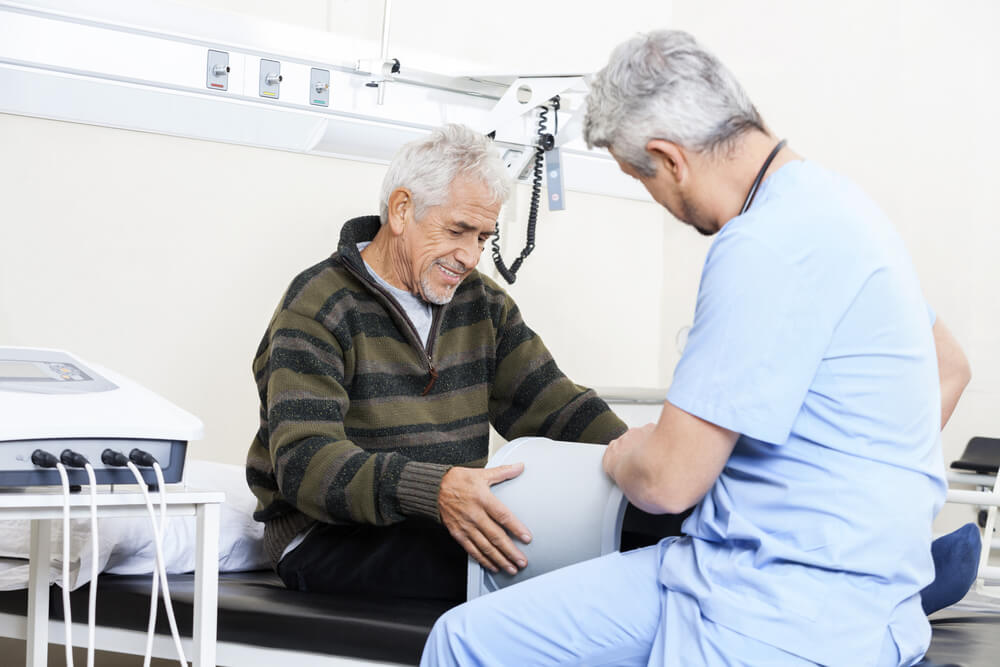 PEMF Trainer Examining Senior Patient On Bed